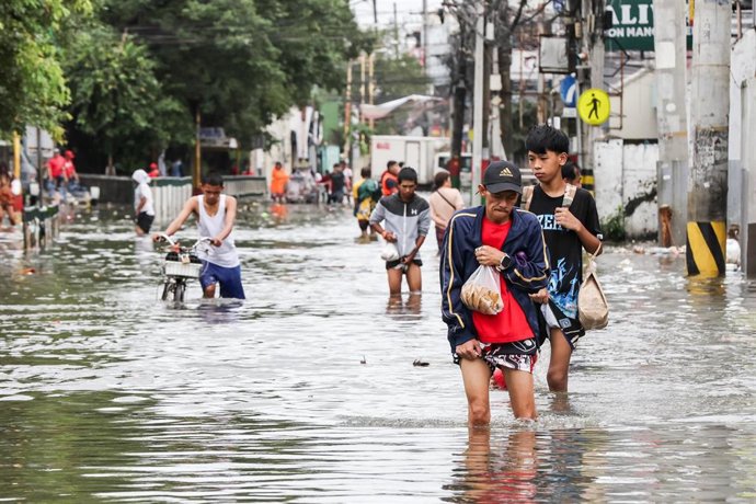 Varias personas caminan entre calles inundadas en Navotas, Filipinas, tras el paso del supertifón 'Fung Wong' (archivo)