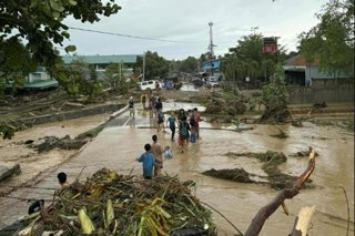 Personas afectadas por los tifones caminan entre el agua y el barro en la provincia de Cebú, Filipinas