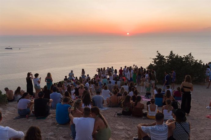 Archivo - Grupos de personas disfrutan del atardecer en una cala de Ibiza.
