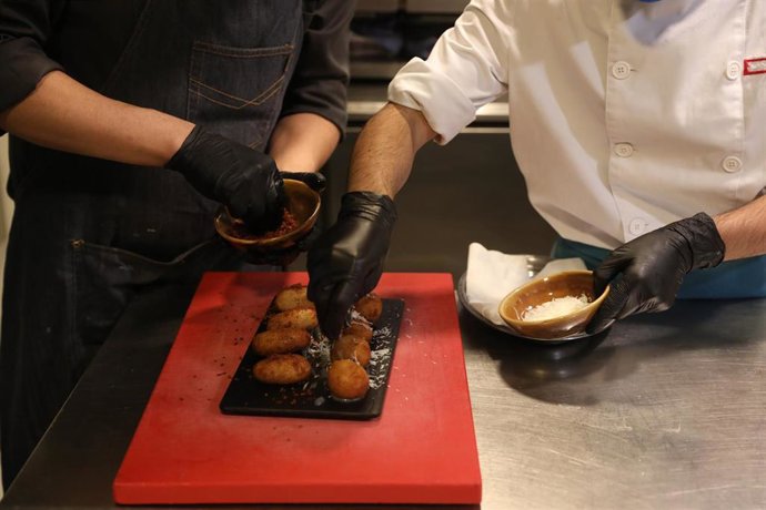 Archivo - Un camarero y un cocinero elaboran un plato en la cocina del Restaurante Marta, Cariño!, en Madrid (España)
