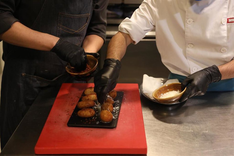 Archivo - Un camarero y un cocinero elaboran un plato en la cocina del Restaurante Marta, Cariño!, en Madrid (España)