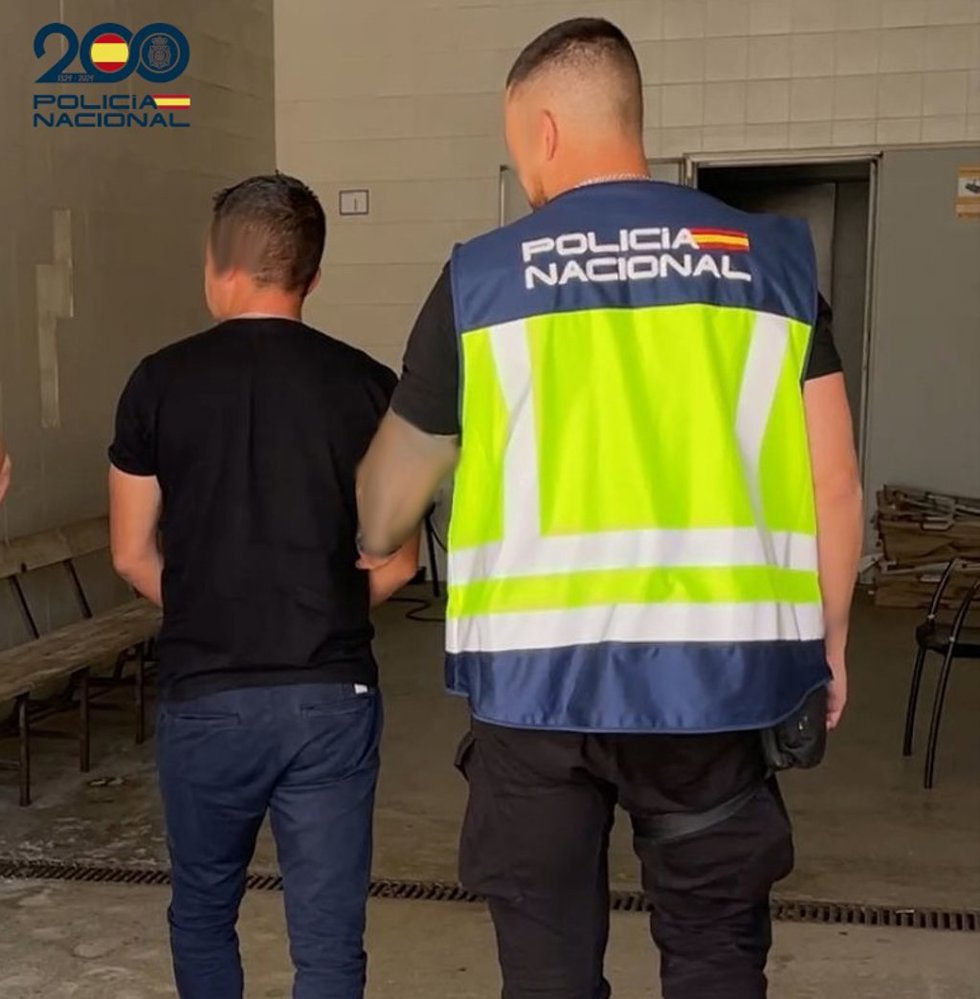 Uno de los arrestados, escoltado por un agente de la Policía Nacional.