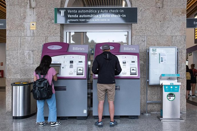 Archivo - Dos personas compran billetes en los cajeros de venta automática en la estación de trenes, a 24  de agosto de 2022, en Santiago de Compostela, A Coruña, Galicia, (España). Los usuarios de Renfe en Galicia pueden adquirir desde hoy los abonos gra