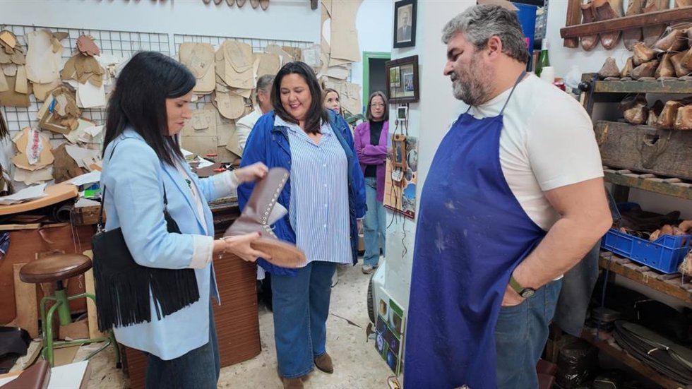 María Dolores Gálvez (izda.) sostiene y observa una bota de Casa Mohedo, acompañada de Lola Amo (centro) y del maestro artesano Manuel Mohedo (dcha.)