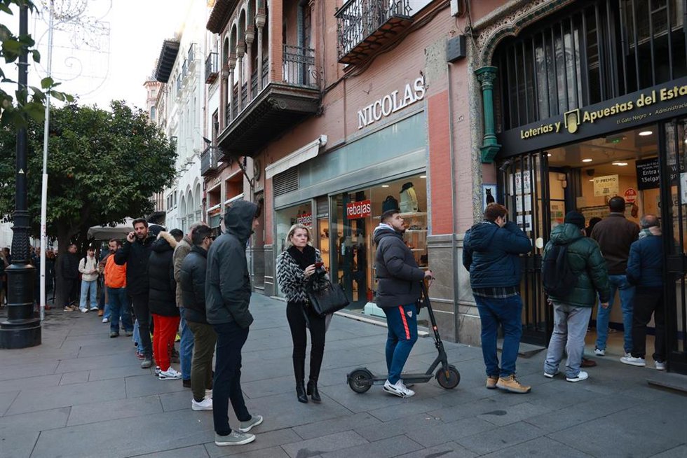Archivo - Decenas de turistas y sevillanos hacen cola para adquirir los últimos décimos de la Lotería de Navidad en la Administración del Gato Negro en la Avenida de la Constitución de Sevilla. Imagen de archivo