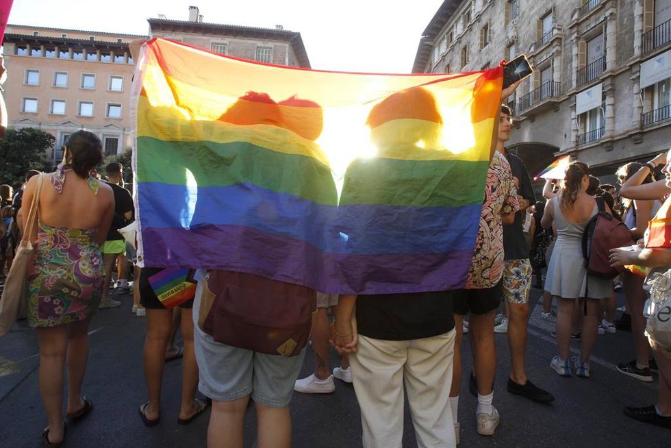 Archivo - Dos personas se tapan con una bandera durante una manifestación por el Orgullo LGTBI.