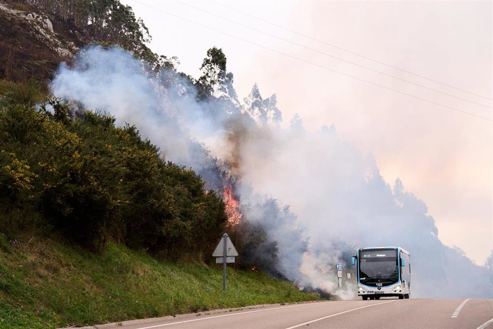 Un vehículo circula por la  CA-170 junto al incendio forestal en Puente Viesgo