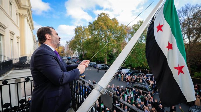 O ministro das Relações Exteriores da Síria, Asaad al Shaibani, levanta a bandeira síria na Embaixada da Síria na capital do Reino Unido, Londres.