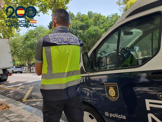 Archivo - Agente de la Policía Nacional junto a un furgón policial.