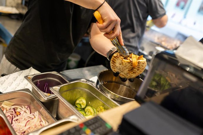 PRODUCTION - 07 November 2025, Baden-Württemberg, Karlsruhe: An employee prepares an Octopus Doener sandwich at the "Pescobar" restaurant.