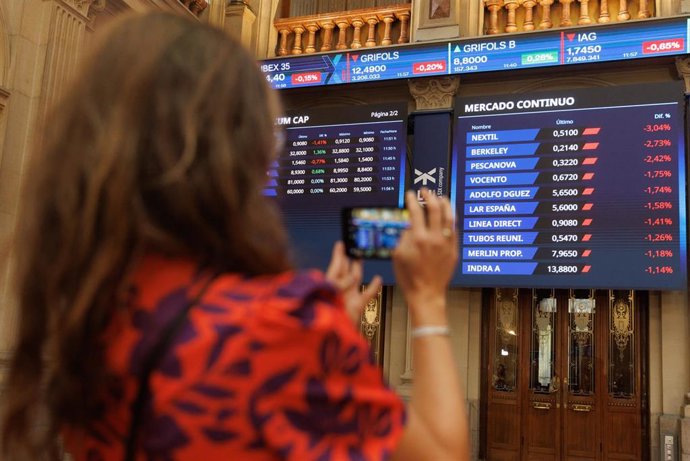 Archivo - Una persona fotografía paneles del Ibex 35 en el Palacio de la Bolsa, a 22 de septiembre de 2023, en Madrid (España).