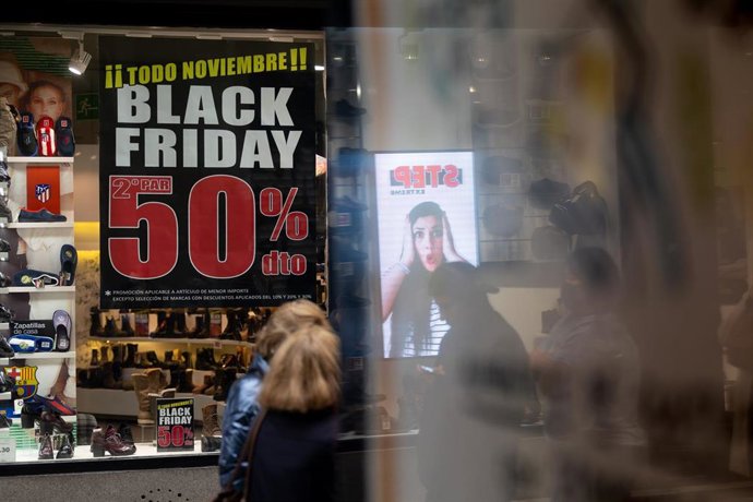 Archivo - Una persona pasa por delante de una tienda que anuncia un cartel publicitario del ‘Black Friday’, a 14 de noviembre de 2022, en Madrid (España).  