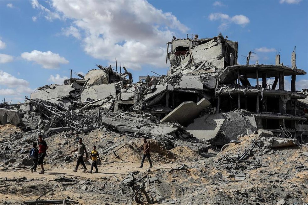 Archivo - Palestinos junto a edificios destruidos en Jan Yunis a causa de la ofensiva de Israel contra la Franja de Gaza (archivo)