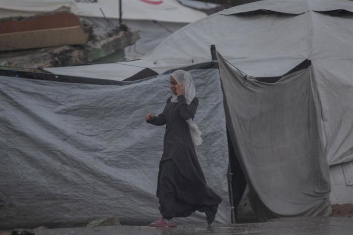 Una mujer palestina camina bajo la lluvia entre las tiendas de desplazados de Gaza 