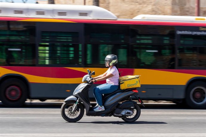 Archivo - Una motocicleta circula junto a un autobús de Tussam-