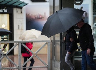 Sevillanos protegiéndose de la lluvia y el viento, protagonistas de la jornada de hoy con avisos naranja y amarillo en gran parte de Andalucía. A 13 de noviembre de 2025, en Sevilla (Andalucía, España). Andalucía vuelve a estar bajo la influencia de inten