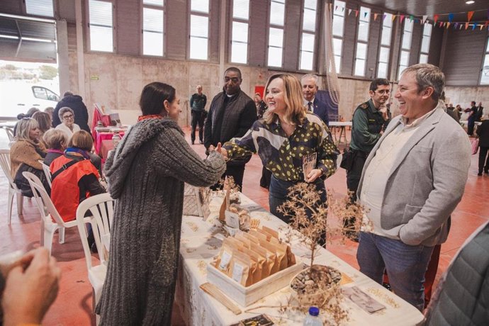 La ministra de Educación, Pilar Alegría, saluda a una mujer en el pabellón de Albalate de Cinca en presencia del alcalde Ricardo Chárlez y del Subdelegado del Gobierno en Huesca, José Carlos Campo.