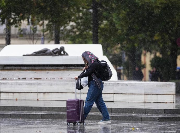 Sevillanos protegiéndose de la lluvia y el viento, protagonistas de la jornada de hoy con avisos naranja y amarillo en gran parte de Andalucía. A 13 de noviembre de 2025, en Sevilla (Andalucía, España). 