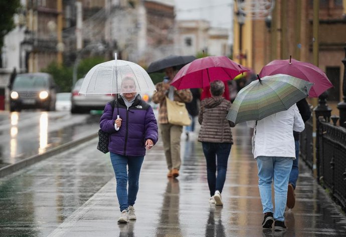 Sevillanos protegiéndose de la lluvia y el viento, protagonistas de la jornada de hoy con avisos naranja y amarillo en gran parte de Andalucía. A 13 de noviembre de 2025, en Sevilla (Andalucía, España). Andalucía vuelve a estar bajo la influencia de inten