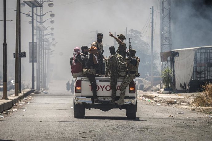 Archivo - 19 July 2025, Syria, As Suwayda: Bedouin and tribal fighters gather in a vehicle in the city of As-Suwayda, as smoke rises from burning houses amid clashes between tribal fighters and local Druze factions in southern Syria. Fear and shock grip t