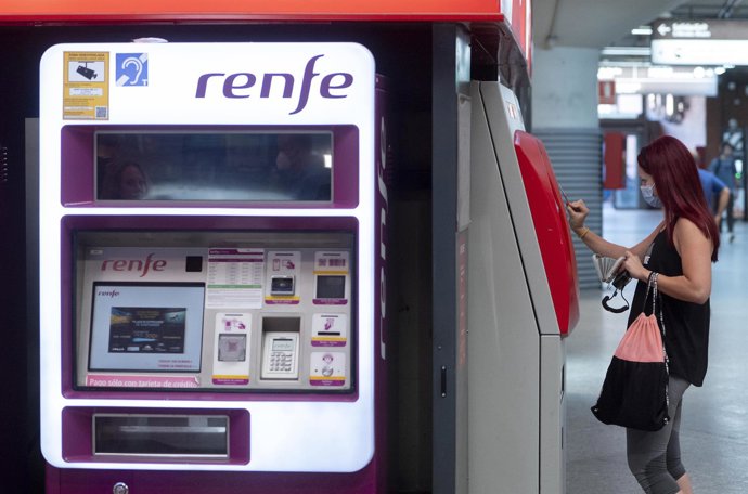 Archivo - Una mujer compra su billete en las taquillas de venta automática de la estación de tren de Atocha