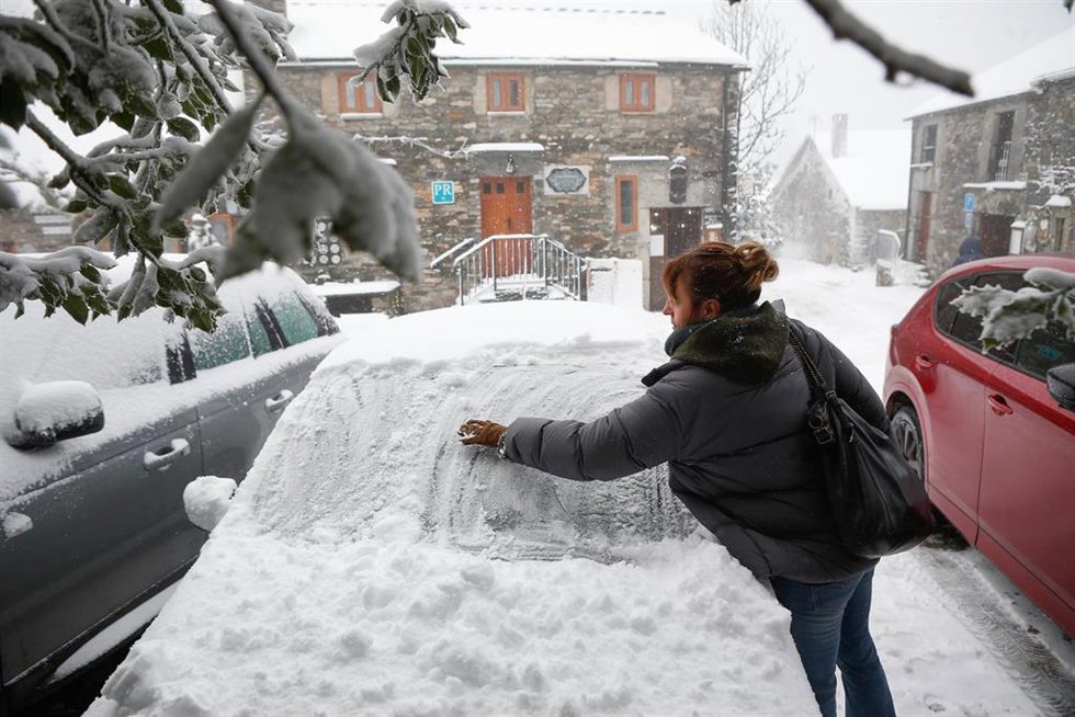 Archivo - Una mujer limpia la nieve de su coche, a 9 de diciembre de 2024, en Pedrafita do Cebreiro, Lugo, Galicia (España).