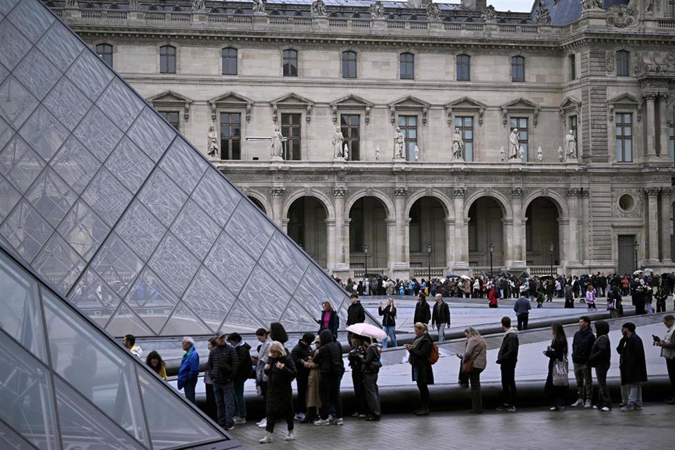 Personas haciendo cola frente a la entrada principal al museo del Louvre de París (archivo)