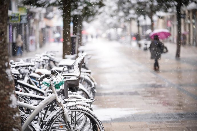 Archivo - Una persona sujeta un paraguas al caminar por una de las calles de Vitoria-Gasteiz tras una intensa nevada (archivo)