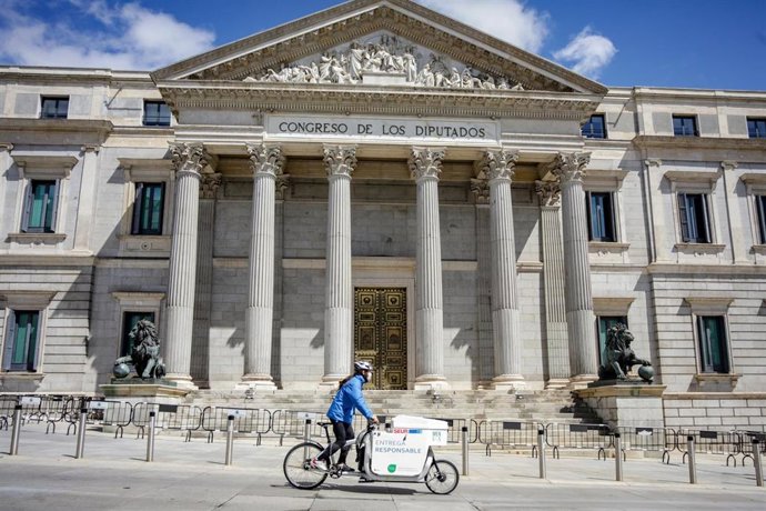 Archivo - Un repartidor pasa por delante del Congreso de los Diputados.