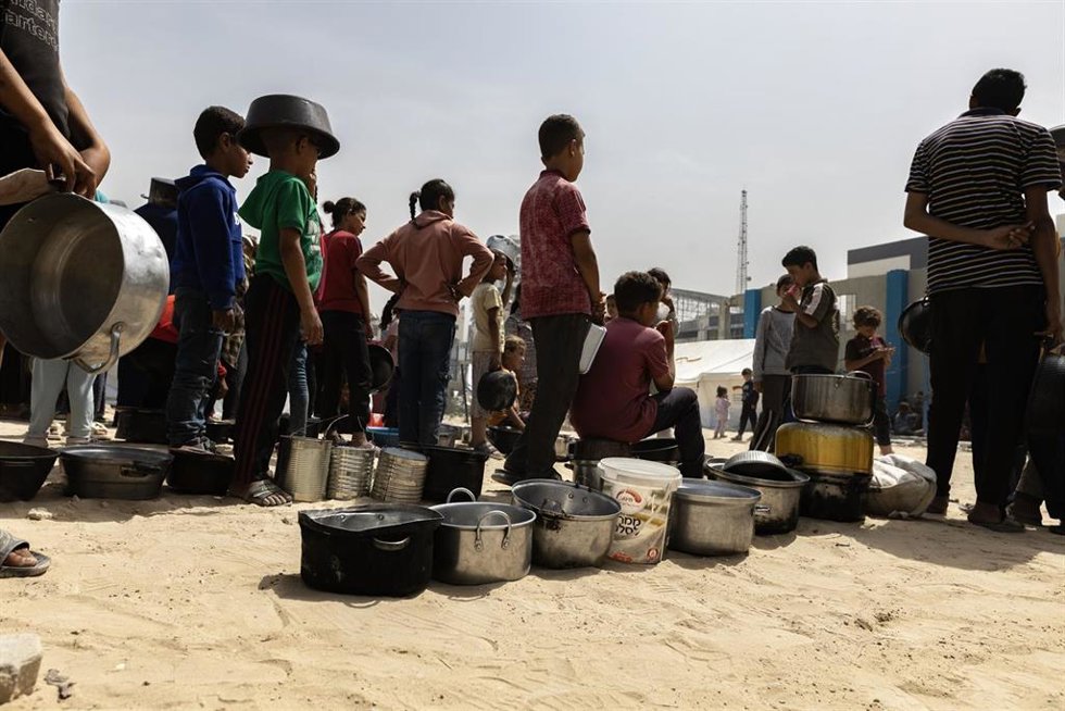 Archivo - Niños palestinos desplazados esperan a recibir comida en la Franja de Gaza