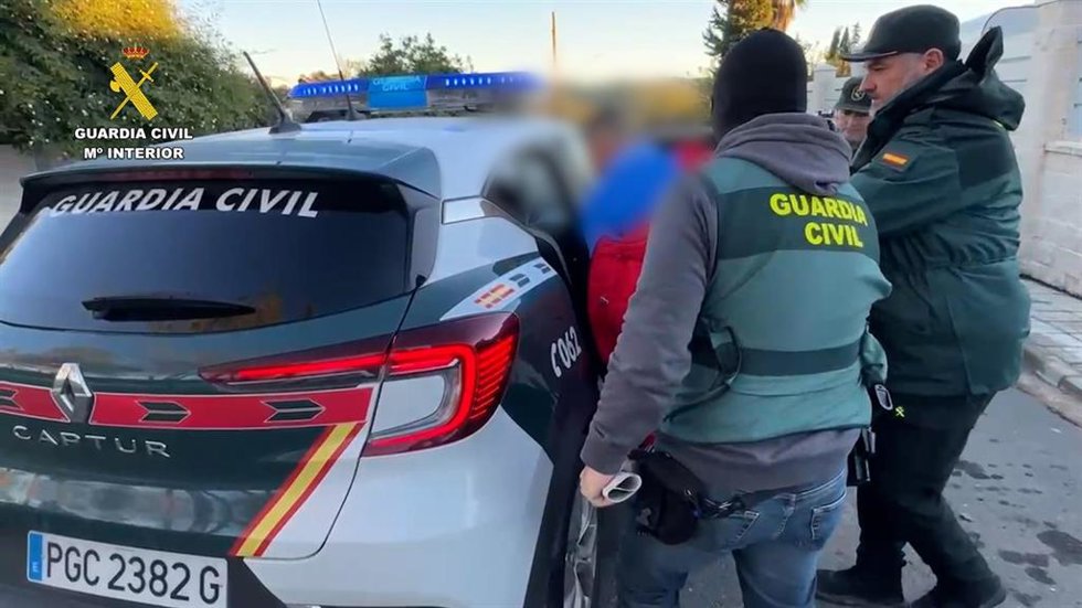 Agentes de la Guardia Civil introducen en el coche a uno de los detenidos por el homicidio de un hombre en Chiclana para robarle droga.