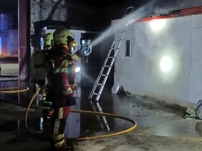 Bomberos del Gobierno de Cantabria durante la extinción del incendio de dos cuartos de herramientas en una nave de Labarces (Valdáliga)