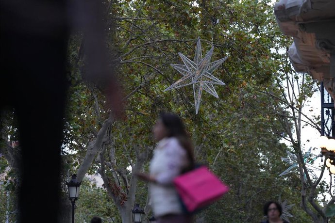 Archivo - Una persona pasa por el Paseo de Gracia, con las luces de Navidad recién colocadas, en una imagen de archivo.