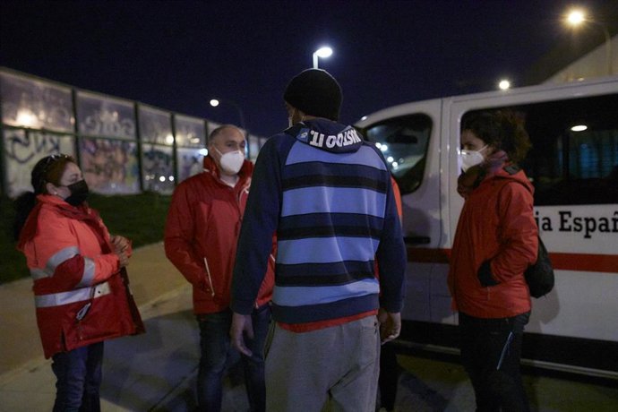 Archivo - Varios trabajadores de Cruz Roja conversan con un hombre sin hogar.