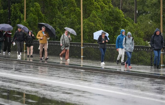 Sevillanos protegiéndose de la lluvia y el viento, protagonistas de la jornada de hoy con avisos naranja y amarillo en gran parte de Andalucía. A 13 de noviembre de 2025, en Sevilla (Andalucía, España). Andalucía vuelve a estar bajo la influencia de inten