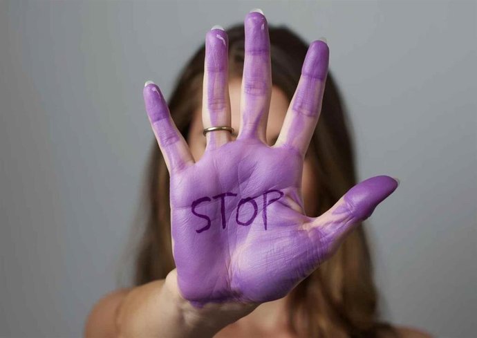 Imagen de archivo una mano pintada de morado contra la violencia machista. 