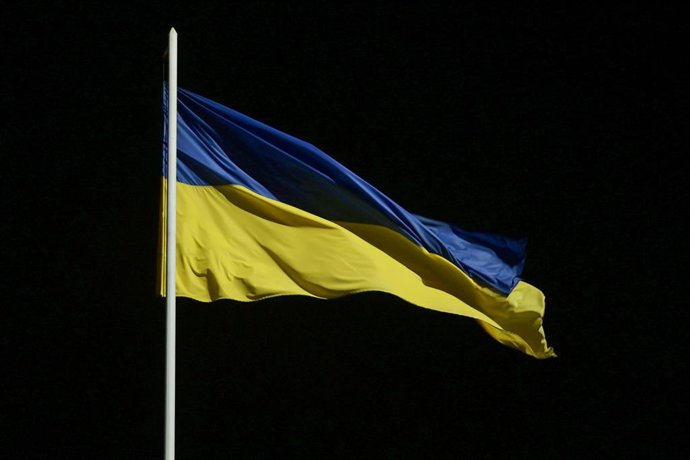 November 15, 2025, Kyiv, Ukraine: Yellow and Blue flag of Ukraine on a flagpole flutters in the wind against a black sky.