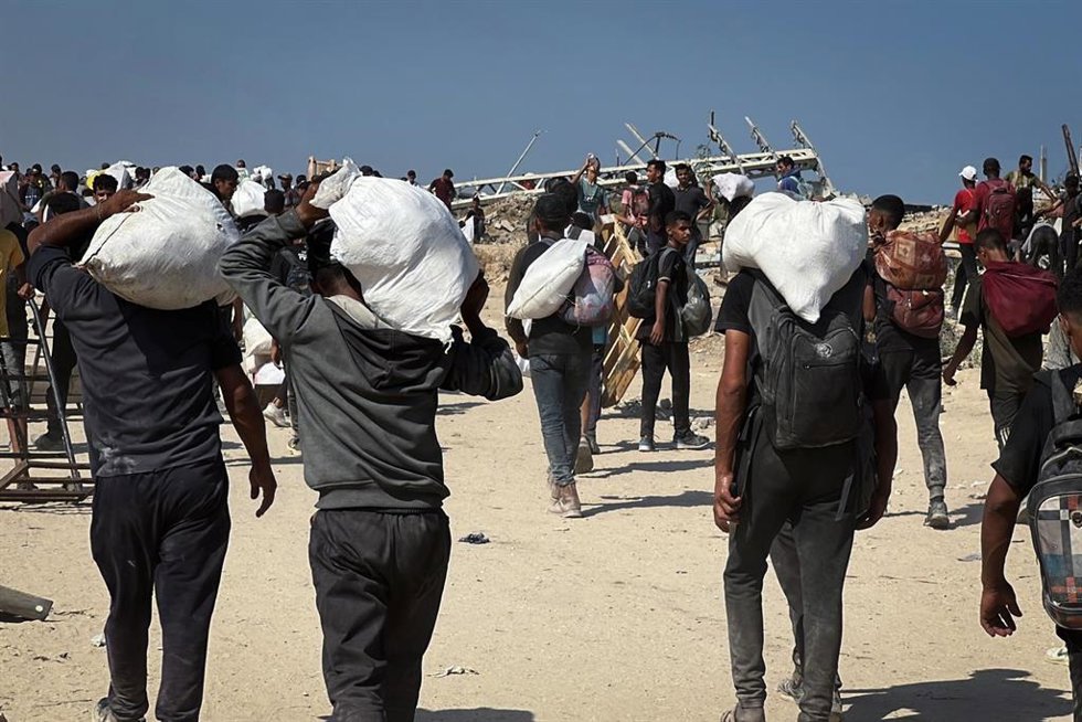 Archivo - Palestinos cargan con paquetes de ayuda recibidos por la Fundación Humanitaria para Gaza (GHF), en Nuseirat, en el centro de la Franja