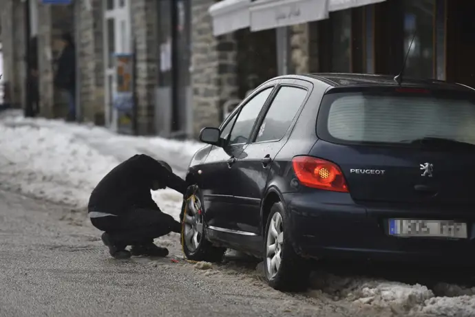 Imagen de un hombre colocando cadenas en las ruedas de su coche. Verónica Lacasa. Archivo.