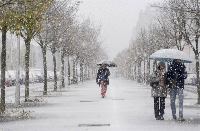 Paseantes cubiertos de nieve durante la llegada de una masa de aire ártico, a 21 de noviembre de 2025, en Vitoria, País Vasco (España).