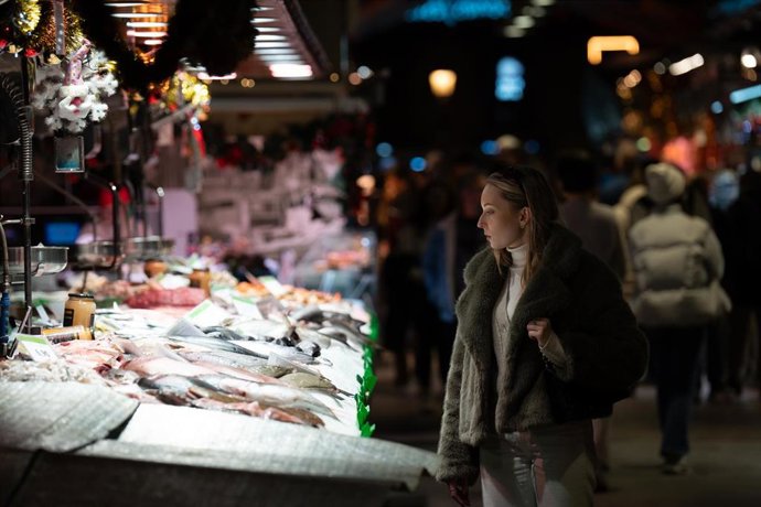 Archivo - Una señora mira el género expuesto, en el mercado de la Boqueria