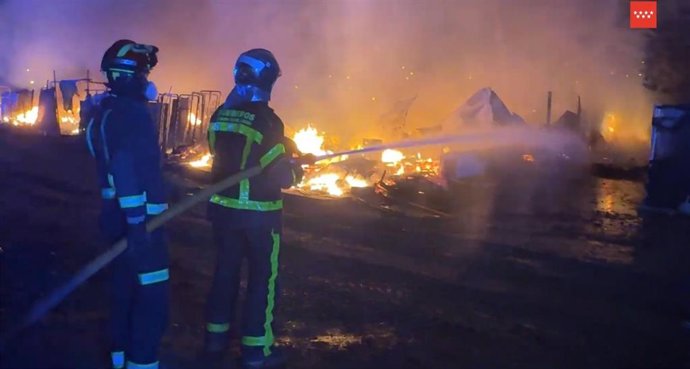 Dos bomberos de la Comunidad de Madrid tratan de apagar un incendio en infraviviendas en Leganés Norte