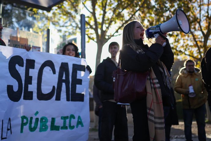 Estudiantes protestan contra la "infrafinanciación" de las universidades y reparten folledos en una parada de autobús de Ciudad Universitaria.