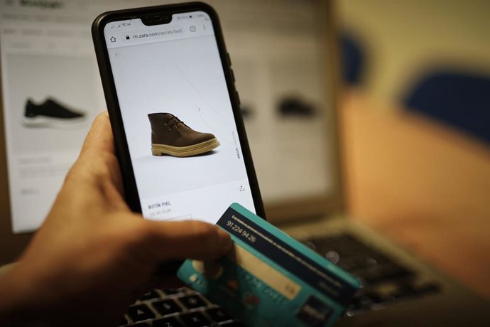 Archivo - Una persona observa en su móvil artículos de moda en la página de un comercio online de moda, en Madrid (España), a 28 de octubre de 2020.