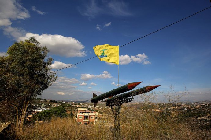 17 de novembro de 2025, Burj Qalaway, Burj Qalaway, Líbano: Uma bandeira pró-iraniana do Hezbollah tremula sobre uma réplica de mísseis apontados para Israel no vilarejo de Burj Qalaway, no sul do Líbano. Israel está construindo um muro no sul do Líbano, 