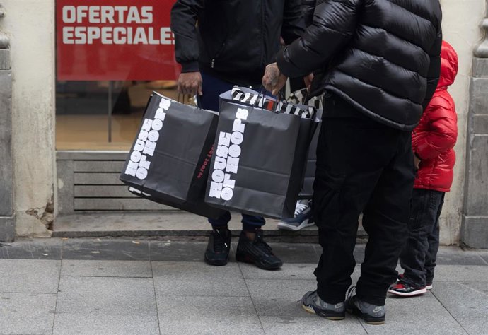 Archivo - Una persona sujeta varias bolsas con compras de Navidad, a 23 de diciembre de 2022, en Madrid (España). 