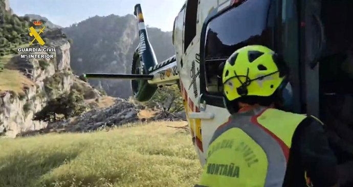 Archivo - Un agente del Greim junto al helicóptero que evacuó a los senderistas. Archivo.