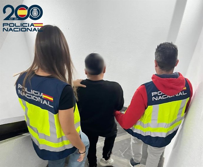 El detenido, de espaldas, custodiado por dos agentes de la Policía Nacional.