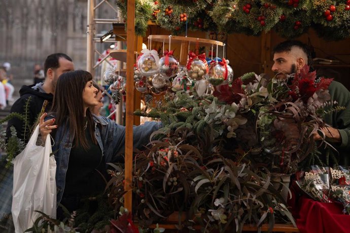 Archivo - Varias personas observan el ambiente navideño en la Fira de Santa Llúcia de Barcelona, en la plaza de la Catedral, a 5 de diciembre de 2024, en Barcelona, Catalunya (España)