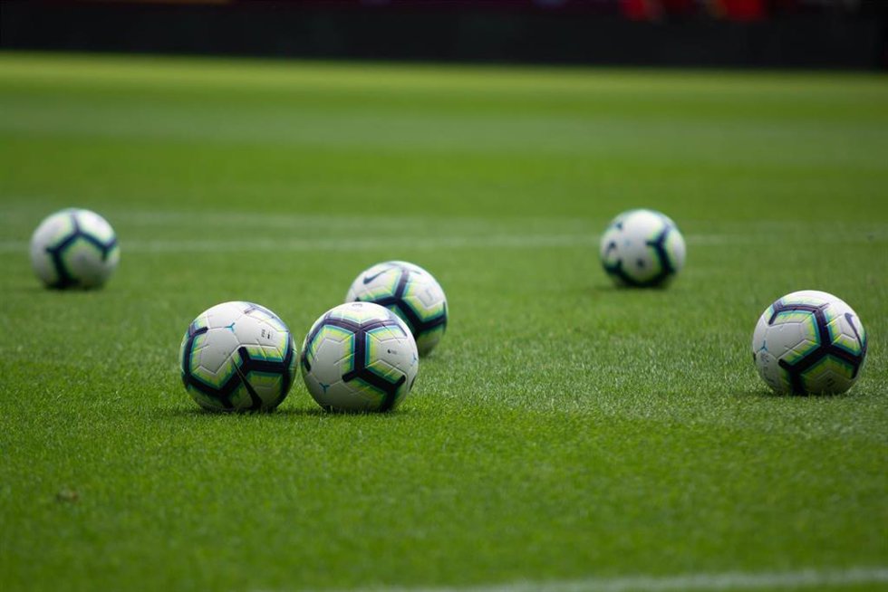 Archivo - Balones de fútbol en un campo